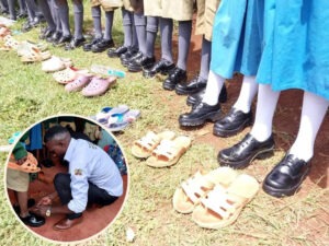 The Dress Me Up Initiative: Dominic Orina's pupils display their new school uniforms and old shoes. In the picture, Orina ties the shoelaces of one of his pupils. Photo/Dominic Orina.
