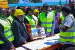 M-Pesa Foundation Project Manager Sam Chege (holding the microphone) explains the construction layout to West Mugirango MP Stephen Mogaka and Nominated MP Irene Mayaka during the groundbreaking and site handing-over ceremony. Photo/Arnold Ageta
